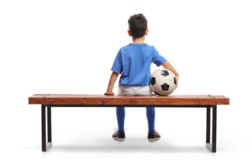 Rear view shot of a boy with a football sitting on a bench