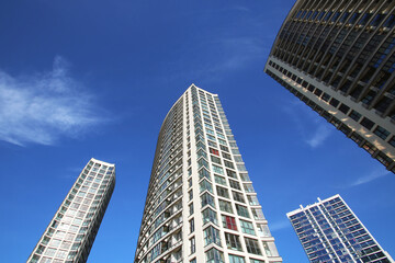 Gazing upward at three towering buildings set against a clear blue sky