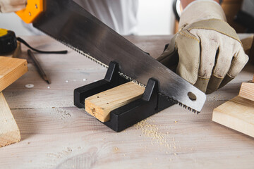 man sawing a wooden beam with a hand saw close-up