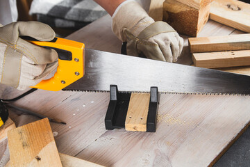 man sawing a wooden beam with a hand saw close-up