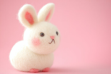 Fototapeta premium Rabbit toy made of felt and wool on a pink background, children's handicraft activities