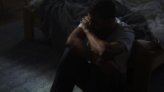 Sad African American calms down with self hugging on floor