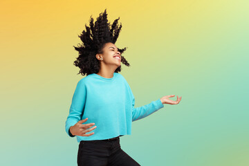 Careless African American young woman dressed in casual clothes dance with invisible guitar over colorful background