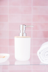 White dispenser in the bathroom on a pink background.