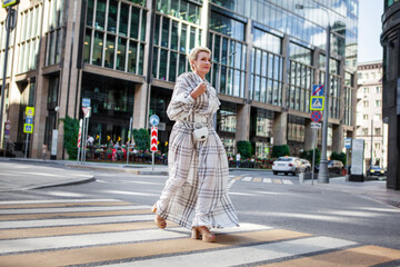 Elegant mature woman wearing white Maxi plaid dress and stylish accessories Walking confidently in...