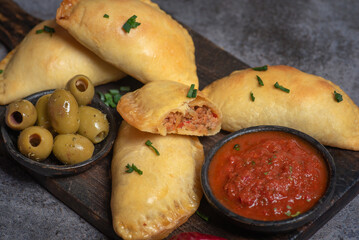 Golden Empanadas with Salsa on a Wooden Board