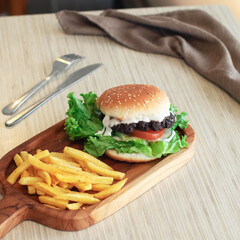 A delicious hamburger is garnished with lettuce and tomato, accompanied by crispy fries, set in a warm dining environment