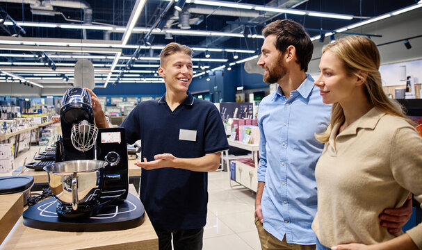 A Sales Associate showcases a kitchen appliance to customers, emphasizing its features
