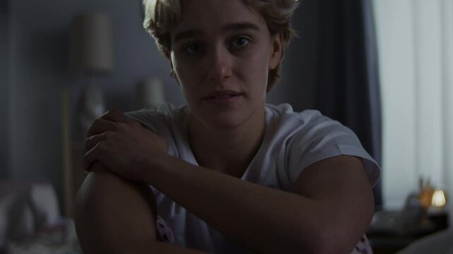 Unhappy woman strokes shoulder feeling uncertain in bedroom