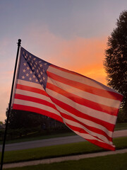 United states flag waving proudly in the wind against a beautiful sunset sky