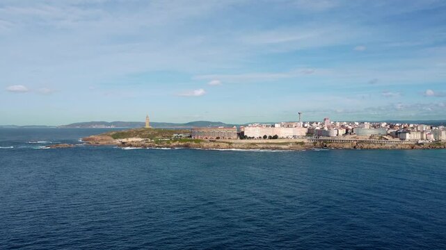 Aerial view of A Coruna city. Drone slowly ascending and panning right from Hercule Tower to historic part of the city. Famous travel destination in Galicia, Spain.