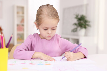 Cute girl drawing at white table in kindergarten