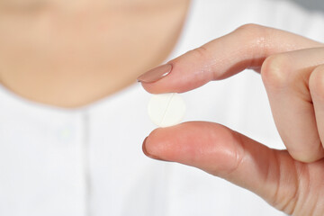 Woman holding antibiotic pill, closeup. Selective focus