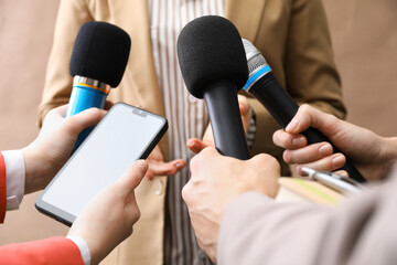 Group of journalists interviewing businesswoman on beige background, closeup