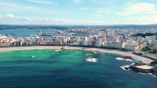 Panoramic aerial view of A Coruna city. Drone panning right. View of all region and city. Old historic center of the city. Orzan Beach. Famous travel destination in Galicia, Spain. Turquoises water.