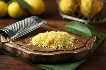 Lemon zest, grater and fresh fruits on wooden table, closeup