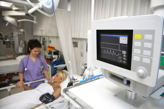 a doctor giving medical treatment at the bedside of a female patient in intensive care in a hospital. Close up of the patient's vital signs on the screen