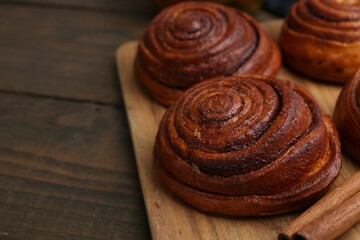 Delicious cinnamon rolls on wooden table, closeup. Space for text