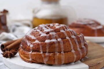 Tasty cinnamon roll with cream and spices on white table, closeup