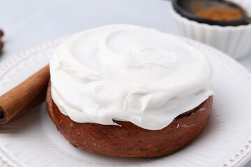 Tasty cinnamon roll with cream and stick on table, closeup