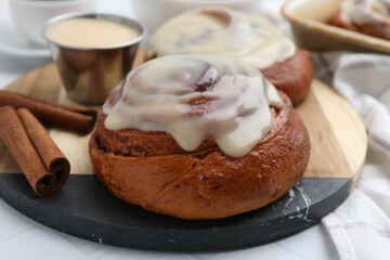 Tasty cinnamon rolls with cream and spices on table, closeup