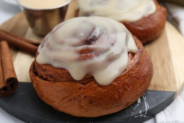 Tasty cinnamon rolls with cream and spices on table, closeup