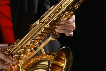 Professional musician with saxophone on black background, closeup