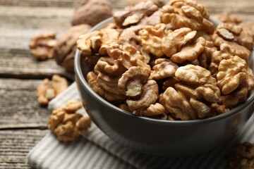 Fresh walnuts in bowl on wooden table, closeup