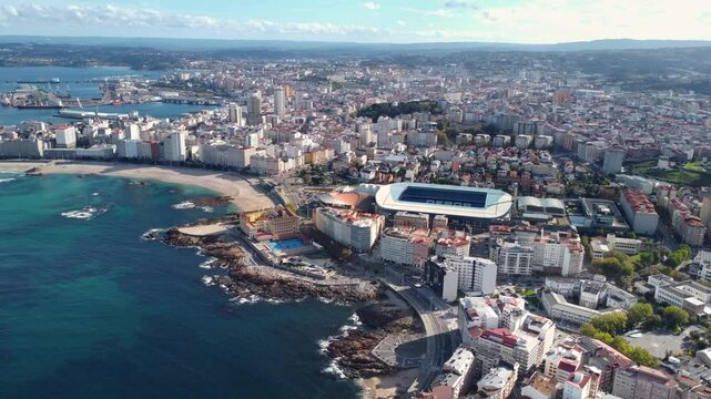 Panoramic aerial view of A Coruna city. View of Riazor Stadium in the middle. Famous travel destination in Galicia, Northwest of Spain. Promenade and beach area of the city. Drone slowly descending.