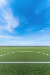 A soccer field with a white line and a white goal. The sky is blue and there are clouds in the background