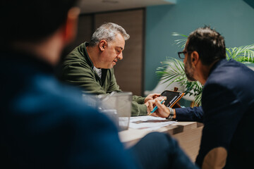 Business colleagues actively discussing and brainstorming together while working on a digital...