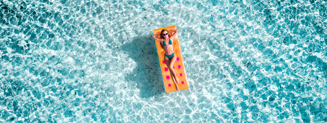 Top above high angle aerial drone view of fit slim thin slender attractive girl floating on rubber mattress clear sea water leisure sunny weather taking sun bath spending celebrating birthday weekend