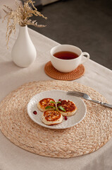 Fragrant fried tvorog pancakes with mint and pomegranate for the perfect breakfast. Table setting. Family Meal Time.