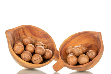 Several macadamia nuts with wooden cup, close-up, isolated on white background.