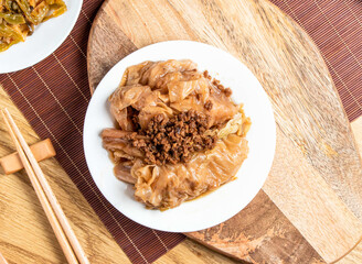 Braised Cabbage with minced Pork meat served in plate with chopsticks and spoon isolated on wooden...