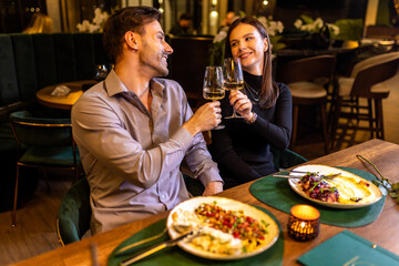 Hands of man and woman toasting with white wine in the restaurant.