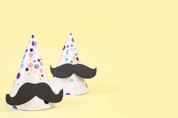 Party hats with paper mustaches on color background