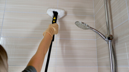 Professional cleaner using a steam cleaner for effectively cleaning bathroom tiles, ensuring...