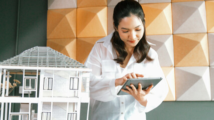 Beautiful project manager using tablet check house model. Portrait of architect engineer inspect building construction by using data analysis from tablet. Business construction concept. Manipulator.