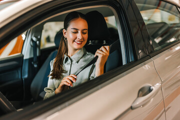 Young businesswoman putting a seatbelt on. Ready to drive off from his parking spot in an underground garage.