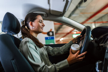 Young woman searching for parking spot in underground garage. Driving around in her car and...