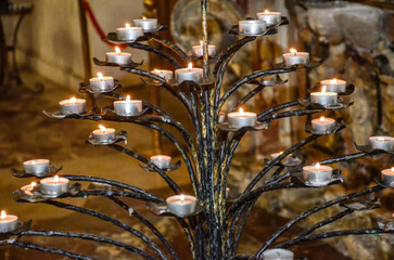 metal candlestick and lit candles in a church in Taormina Sicily