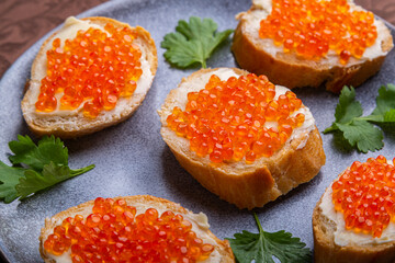 Canapes with red caviar on a plate decorated with cilantro