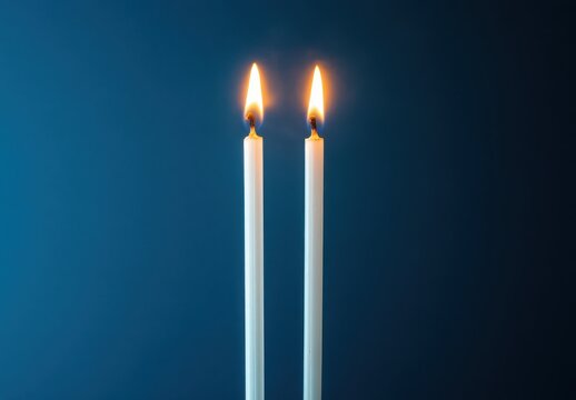 Two White Candles Burning with Flickering Flames on a Dark Blue Background for Peaceful and Elegant Candlelight Atmosphere