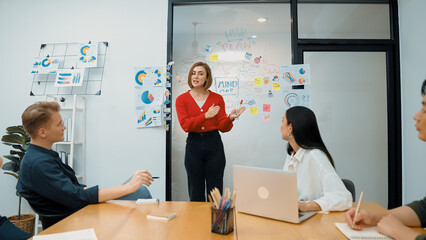 Young beautiful leader presents marketing strategy while expert investor and project manager listening and lecturing to analyze business performance at start up business meeting. Immaculate.