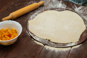 Thin dough on a wooden table on a round baking board for Purim