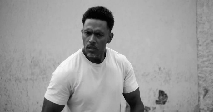 Man in fighting stance fists raised calling out the camera for a fight, direct confrontation conflict aggression tension assertive body language challenge, provocation intense eye contact street fight