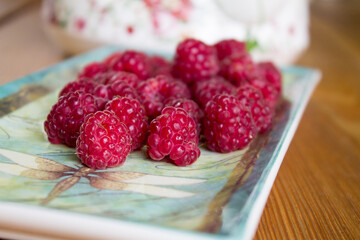 A pile of fresh raspberries on a plate. Fresh natural farm product. Summer mood.
