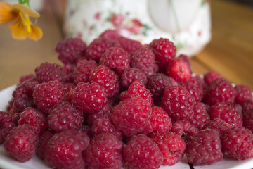 A pile of fresh raspberries on a plate. Fresh natural farm product. Summer mood.