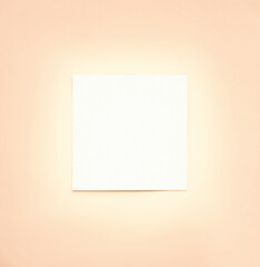 Blank square paper sheet displayed against a soft pastel peach background offering creative...